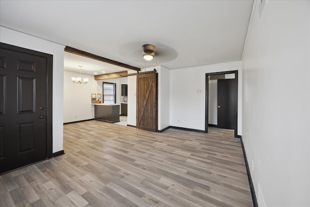 interior space featuring ceiling fan with notable chandelier, a barn door, and light hardwood / wood-style flooring