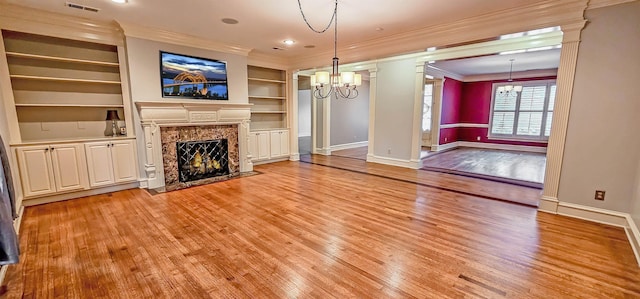 unfurnished living room with crown molding, a high end fireplace, light hardwood / wood-style floors, and a chandelier