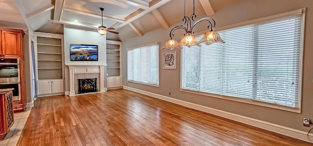 unfurnished living room featuring lofted ceiling with beams, a tile fireplace, plenty of natural light, and light wood-type flooring