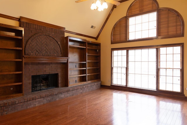 unfurnished living room with crown molding, a fireplace, high vaulted ceiling, and wood-type flooring