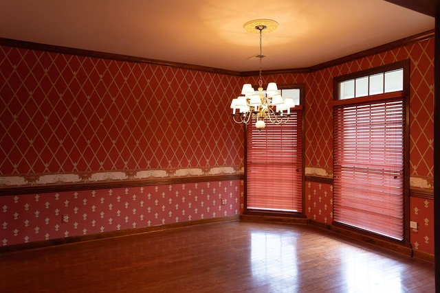 unfurnished dining area with hardwood / wood-style floors, crown molding, and a chandelier