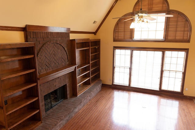 living room featuring ceiling fan, wood-type flooring, a fireplace, and ornamental molding