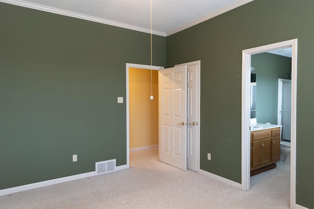 unfurnished bedroom with crown molding, light carpet, and ensuite bath