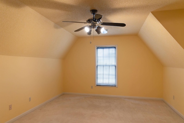 bonus room featuring ceiling fan, vaulted ceiling, light colored carpet, and a textured ceiling