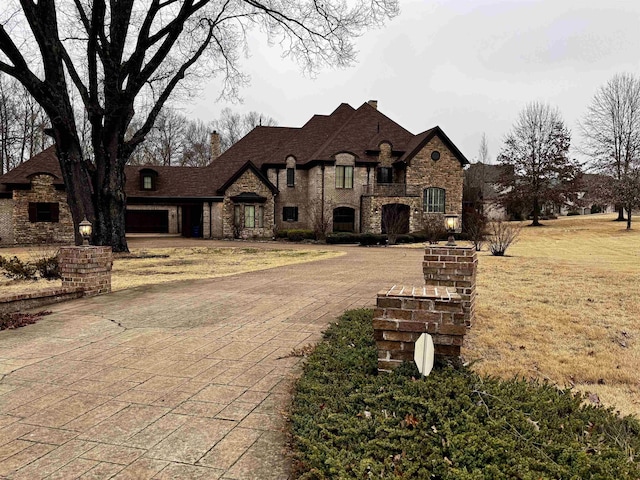 french country inspired facade featuring a garage and a front lawn