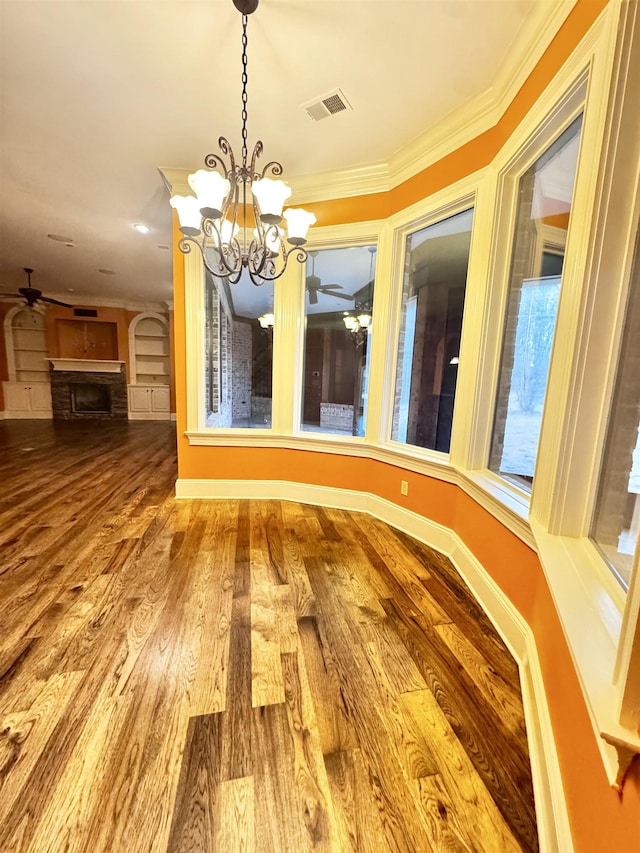 unfurnished dining area featuring crown molding, wood-type flooring, and ceiling fan with notable chandelier