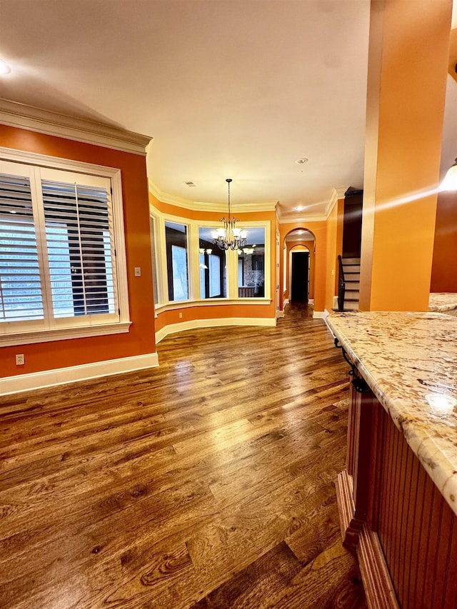 unfurnished living room with ornamental molding, dark hardwood / wood-style floors, and a chandelier