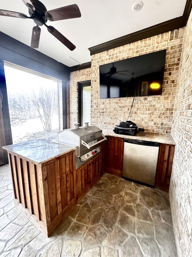 kitchen with light stone counters, ornamental molding, fridge, and brick wall