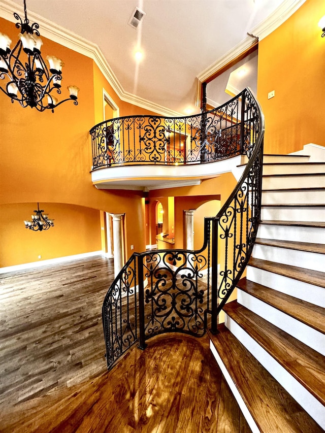 stairway with a notable chandelier, hardwood / wood-style flooring, and ornamental molding