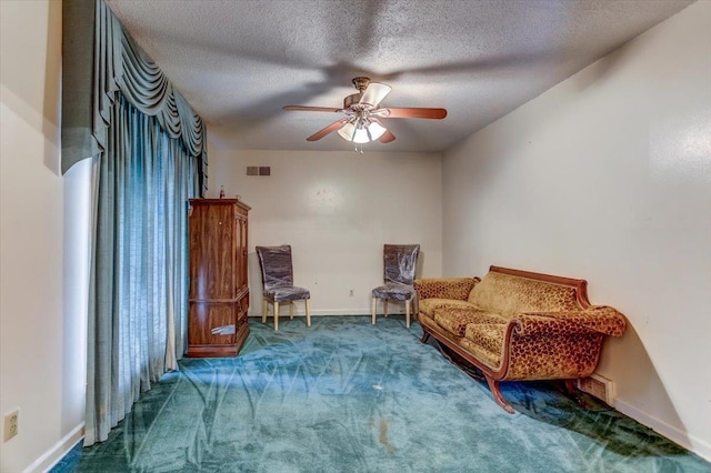 sitting room featuring ceiling fan, a textured ceiling, and carpet