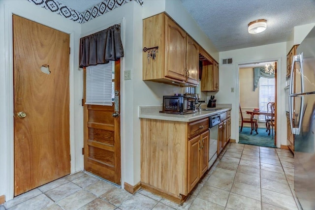 kitchen with stainless steel appliances, sink, a textured ceiling, and light tile patterned floors