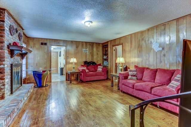 living room with a textured ceiling, a fireplace, and wood-type flooring