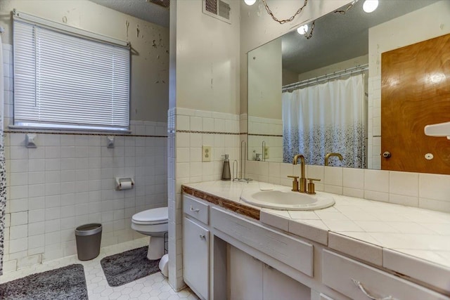 bathroom featuring tile walls, vanity, a textured ceiling, tile patterned floors, and toilet