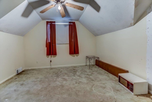 additional living space featuring vaulted ceiling, light colored carpet, a textured ceiling, and ceiling fan