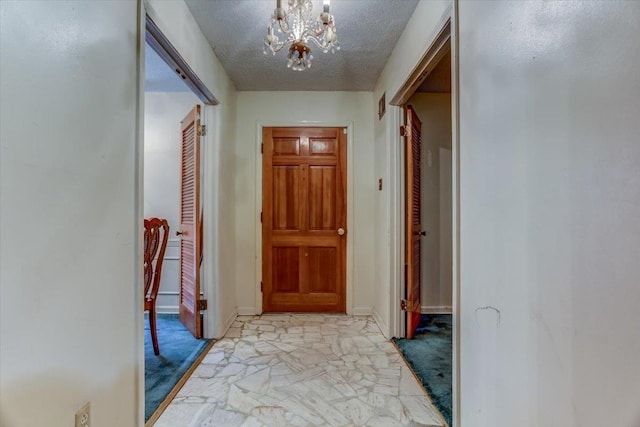 hall with a notable chandelier and a textured ceiling