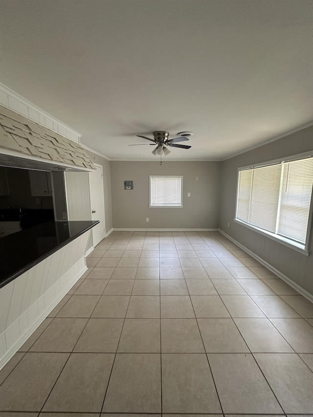 unfurnished living room with crown molding, ceiling fan, and light tile patterned floors