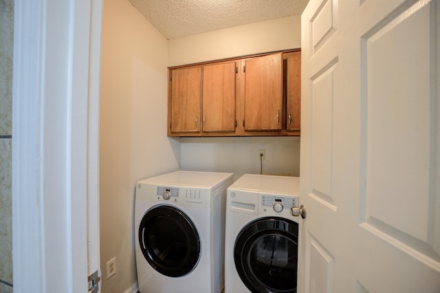 washroom featuring washer and clothes dryer, cabinets, and a textured ceiling