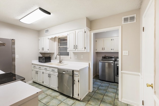 kitchen featuring sink, appliances with stainless steel finishes, white cabinetry, a textured ceiling, and washing machine and clothes dryer