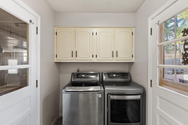 clothes washing area with cabinets, washing machine and dryer, and a textured ceiling