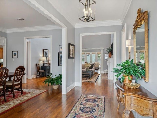 foyer entrance featuring a notable chandelier, dark wood-type flooring, and ornamental molding