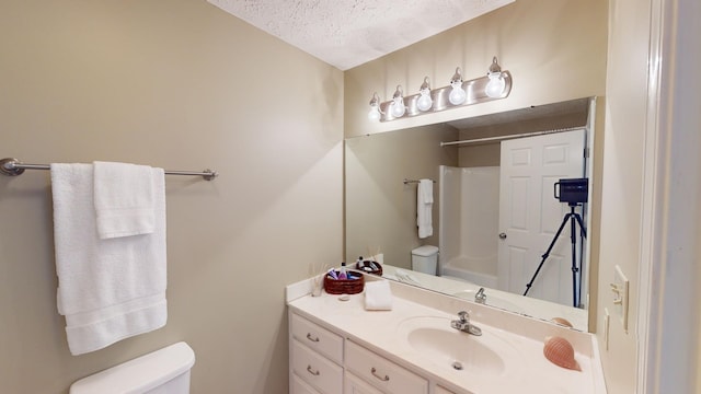 bathroom with vanity, toilet, and a textured ceiling