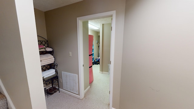 hallway with light colored carpet and a textured ceiling