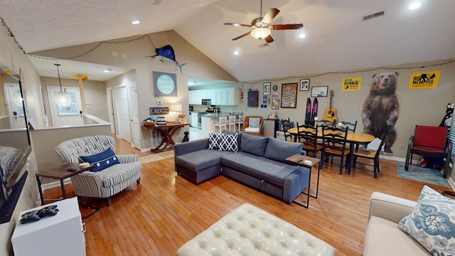 living room featuring lofted ceiling, ceiling fan, and light hardwood / wood-style flooring