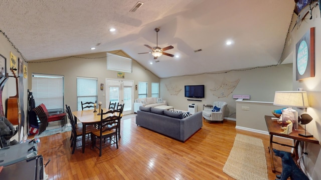 living room with vaulted ceiling, a textured ceiling, light hardwood / wood-style floors, and french doors