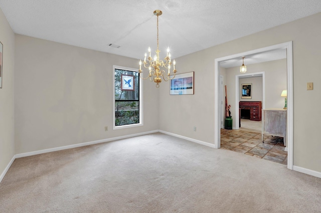 empty room featuring light colored carpet, a notable chandelier, a brick fireplace, and a textured ceiling