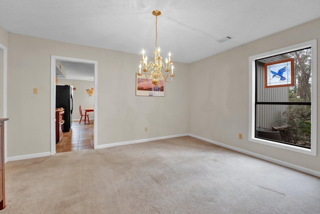 empty room with light carpet, a notable chandelier, and a textured ceiling