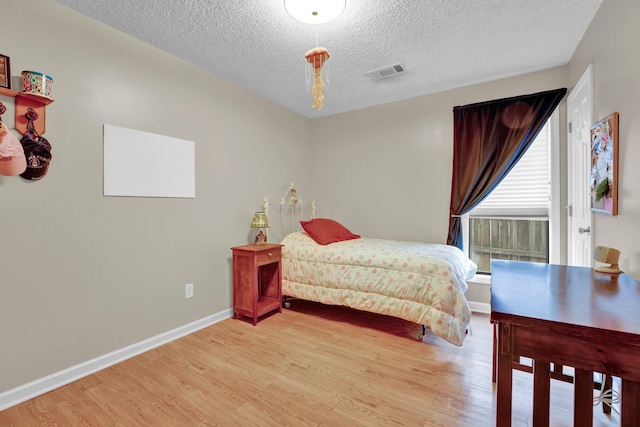 bedroom with a textured ceiling and light wood-type flooring