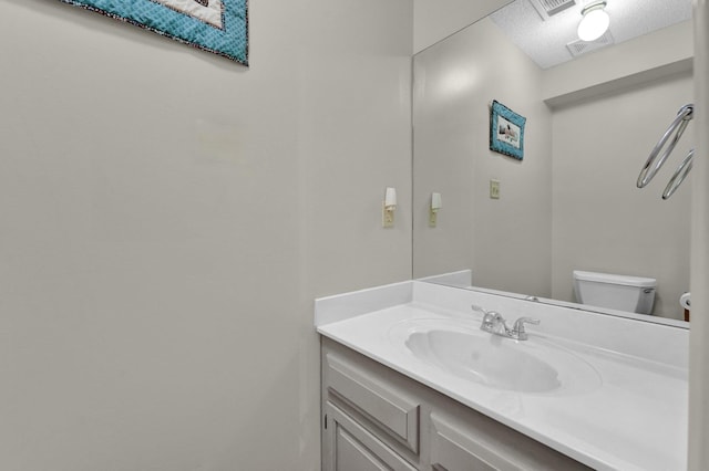 bathroom featuring vanity, toilet, and a textured ceiling