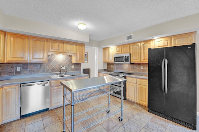 kitchen featuring stainless steel appliances, light brown cabinetry, sink, and decorative backsplash