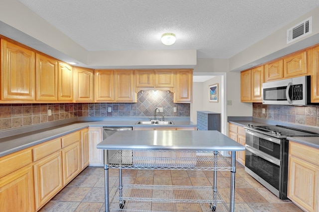 kitchen featuring appliances with stainless steel finishes, light brown cabinetry, sink, backsplash, and a textured ceiling