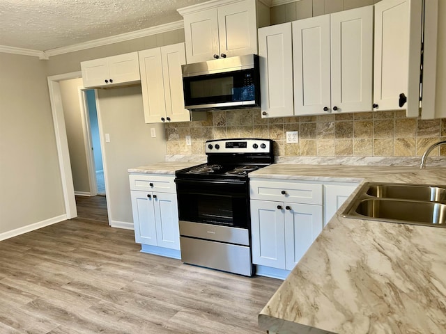 kitchen featuring stainless steel appliances, white cabinetry, sink, and crown molding