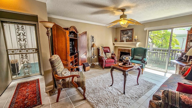 living area featuring ceiling fan, a fireplace, ornamental molding, a textured ceiling, and light tile patterned flooring