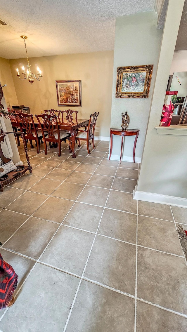 dining space featuring tile patterned floors, a textured ceiling, and a notable chandelier