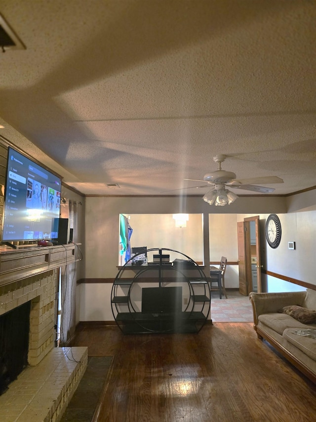 living room with ceiling fan, a textured ceiling, a fireplace, and wood-type flooring