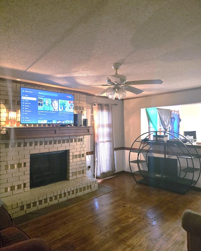 living room with a brick fireplace, wood-type flooring, a textured ceiling, and ceiling fan