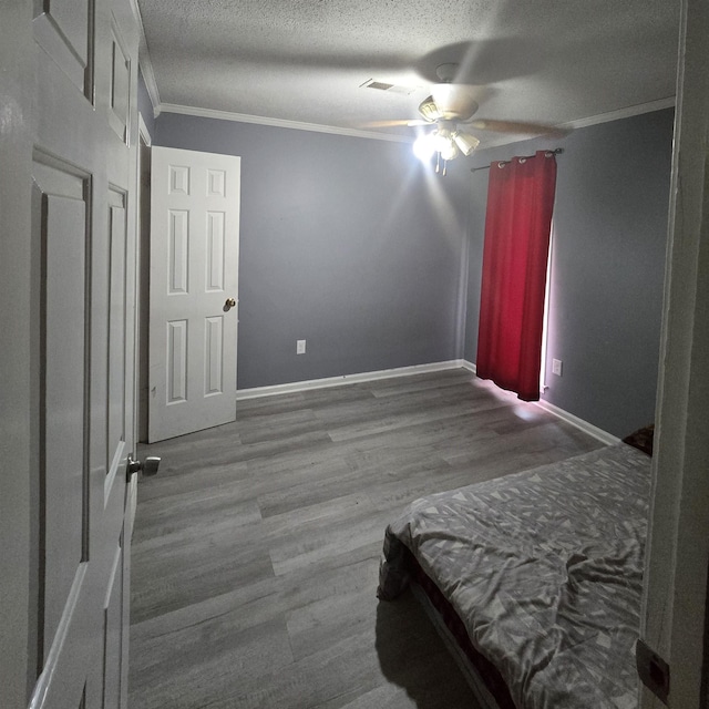 bedroom with ceiling fan, crown molding, wood-type flooring, and a textured ceiling