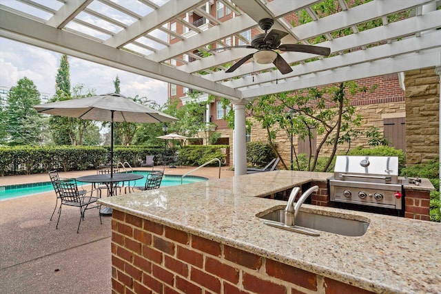 view of patio / terrace featuring a fenced in pool, a pergola, a grill, an outdoor wet bar, and exterior kitchen