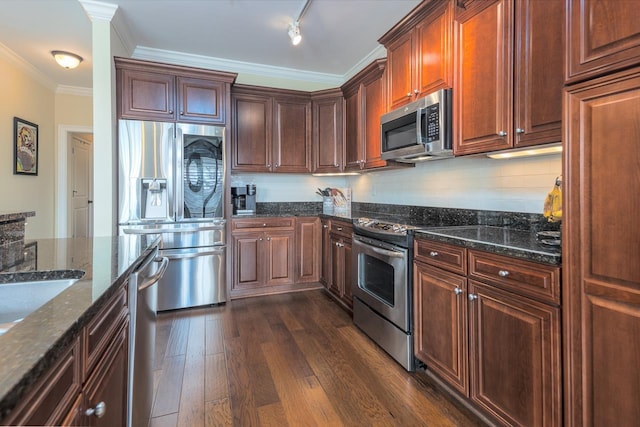 kitchen featuring crown molding, appliances with stainless steel finishes, dark wood-type flooring, and dark stone countertops