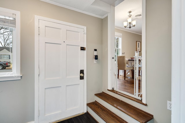 foyer entrance with an inviting chandelier, dark hardwood / wood-style flooring, crown molding, and a wealth of natural light