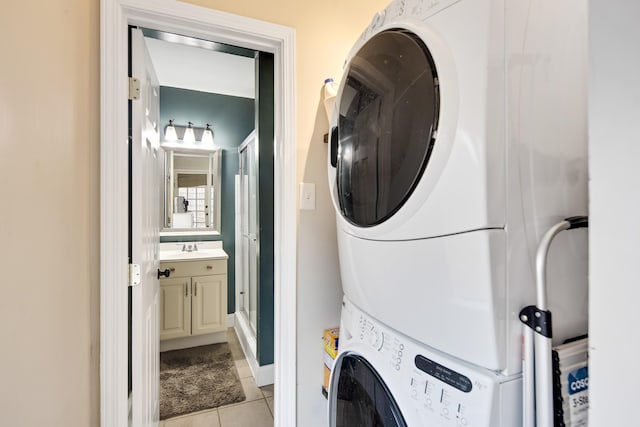 laundry room featuring light tile patterned floors, sink, and stacked washer / dryer