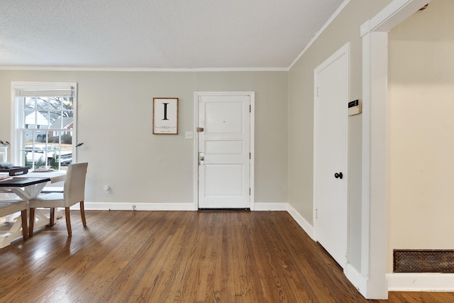 foyer entrance with dark hardwood / wood-style flooring, ornamental molding, and a textured ceiling