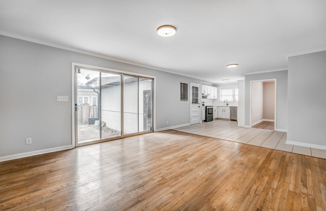 unfurnished living room with ornamental molding, sink, and light wood-type flooring