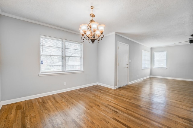 empty room with wood-type flooring, ornamental molding, and a textured ceiling