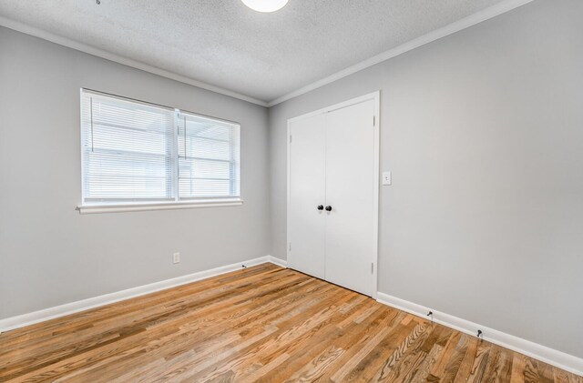 empty room with crown molding, light hardwood / wood-style flooring, and a textured ceiling