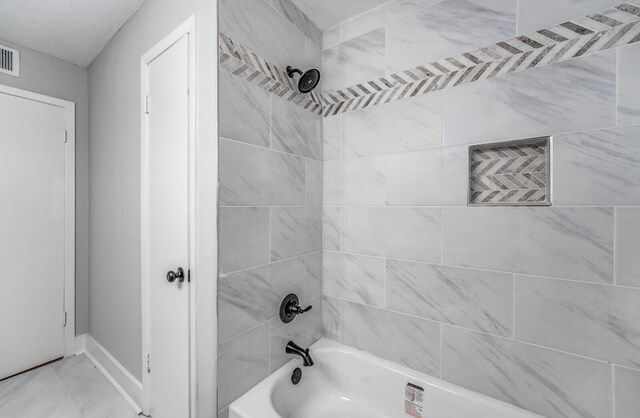 bathroom with tiled shower / bath and a textured ceiling