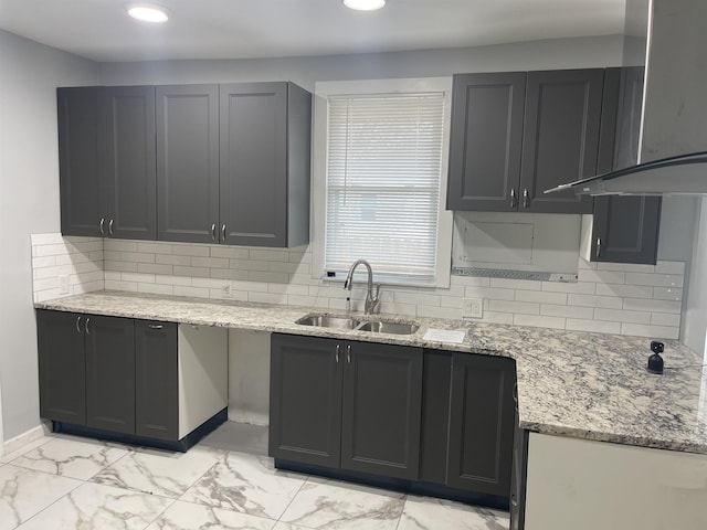 kitchen with tasteful backsplash, sink, exhaust hood, and light stone counters